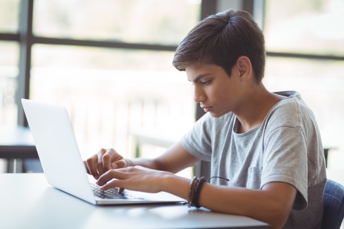 A student taking a test on his laptop by the window